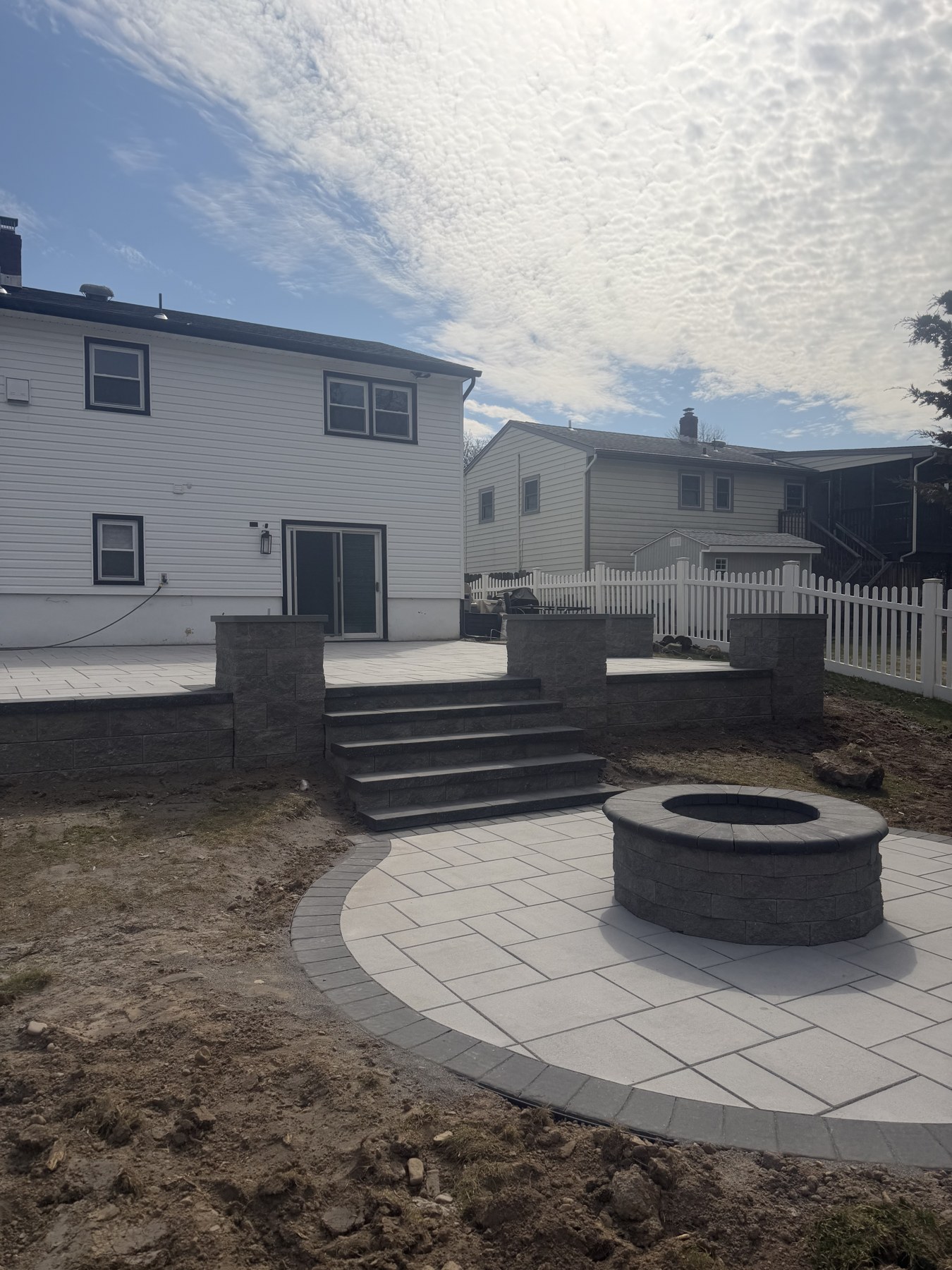 JK Masonry backyard patio with stone steps and a circular fire pit